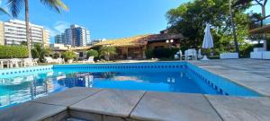 uma piscina com água azul em frente a um edifício em Solar Praia Dourada em Ilhéus