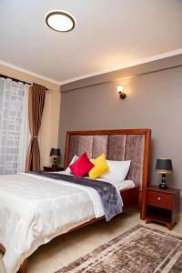 Un dormitorio con una cama con almohadas de colores. en Azarel homes, en Kampala