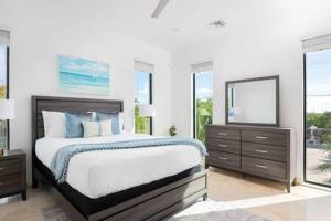 a bedroom with a bed and a mirror and windows at Gated Long Bay Villa Near Grace Bay with Pool in Long Bay Hills