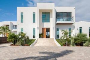 ein weißes Gebäude mit Palmen davor in der Unterkunft Private Pool Villa, Long Bay Beach with VIP Extras in Long Bay Hills