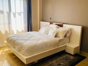 Una cama con sábanas blancas y almohadas en un dormitorio en Azarel homes, en Kampala
