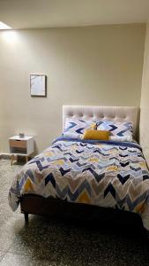 a bedroom with a bed with a blue and white comforter at Lindo espacio, cómodo y céntrico in San Salvador