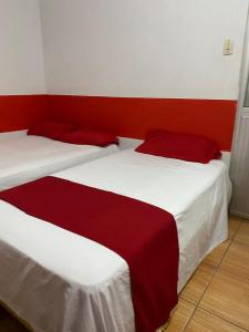 two beds in a room with red and white at Hotel Paraiso in Portoviejo