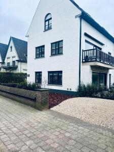 Cette maison blanche dispose d'un balcon. dans l'établissement Gelijkvloers appartement met aansluitende parking, à Knokke-Heist