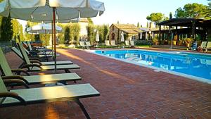 a swimming pool with benches and umbrellas next to at Agriturismo La Sovana in Sarteano