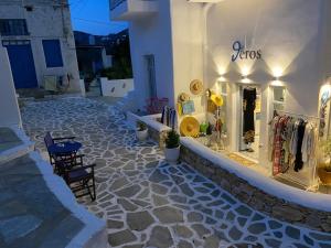 a store on a white building with a table and chairs at Theros Apartments Donoussa in Donoussa