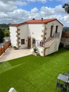 una pequeña casa blanca con césped verde en PENSION ORUEIRO VILASERIO, en Negreira