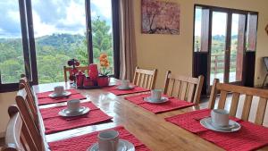 a dining room table with red napkins and chairs with a view at Casa Sossego na Montanha in Campos do Jordão