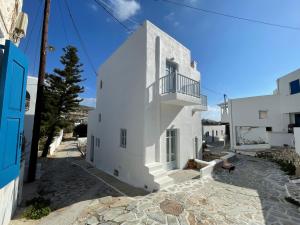 a white building with a balcony on a street at Theros Apartments Donoussa in Donoussa