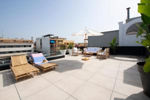 patio z krzesłami i parasolem na dachu w obiekcie Apartamentos Balisse w mieście Castelldefels