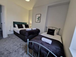 2 camas en una habitación pequeña con faldas en 5 Bedroom modern home with parking. Near Brecon Beacons & Bike Park Wales, en Merthyr Tydfil