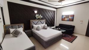 a hotel room with two beds and a couch at Aleph Islamabad Guest House in Islamabad