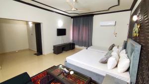 a bedroom with a white bed and a tv at Aleph Islamabad Guest House in Islamabad