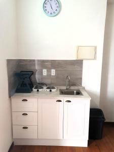 una cocina con fregadero y un reloj en la pared en Catherine Suites en Willemstad