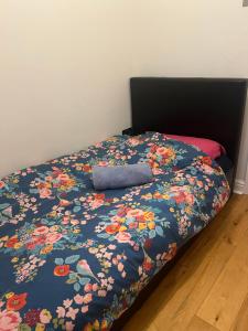 ein Bett mit einer blauen Decke mit Blumen drauf in der Unterkunft Ilford Tiny Jewel in Ilford