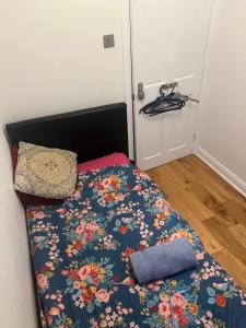 a bed with a floral comforter and a pillow at Ilford Tiny Jewel in Ilford