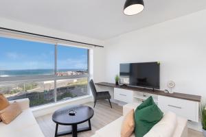 a living room with a white couch and a large window at Blouberg Heights 207 in Bloubergstrand