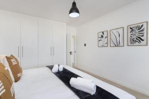 een witte slaapkamer met een bed met 2 kussens bij Blouberg Heights 207 in Bloubergstrand