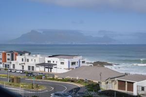a group of white houses next to the ocean at Blouberg Heights 207 in Bloubergstrand