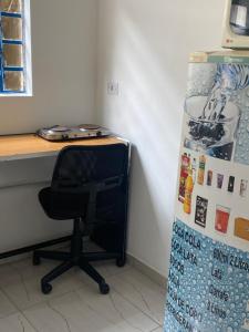 a desk with a chair next to a refrigerator at Edículas da vivi in Sao Paulo