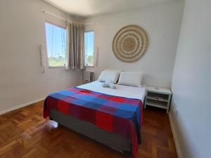 a bedroom with a bed with a colorful blanket on it at Seaside Season Maceió in Maceió