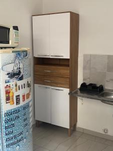 a kitchen with a refrigerator and a white cabinet at Edículas da vivi in Sao Paulo