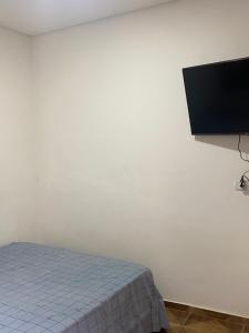 a bedroom with a bed and a flat screen tv on a wall at Edículas da vivi in Sao Paulo