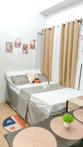 2 Betten in einem Zimmer mit Vorhängen und Tischen in der Unterkunft Anuva Stays in Manila