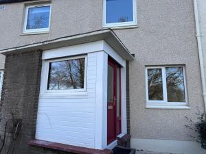 a garage with a red door and two windows at 4 Bed House, Glenrothes sleeps 5 in Fife