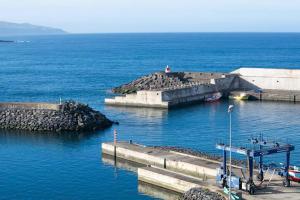 a dock in the water with a lighthouse on it at A Casa da Concha in Rabo de Peixe