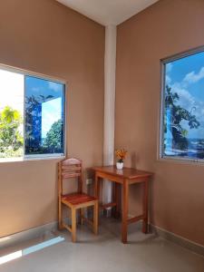 a table and a chair in a room with two windows at Casa Alojamiento Picuro Lodgind in Iquitos