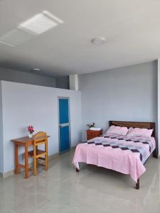 a bedroom with a large bed and a table at Casa Alojamiento Picuro Lodgind in Iquitos