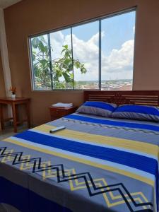 a large bed in a bedroom with a large window at Casa Alojamiento Picuro Lodgind in Iquitos