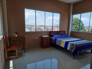 a bedroom with a bed and windows with a view at Casa Alojamiento Picuro Lodgind in Iquitos