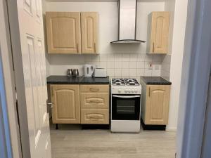 uma cozinha com armários de madeira e um forno com placa de fogão em London Stratford 4 Bedrooms Apartment em Londres