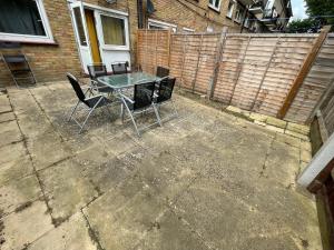 un patio con mesa, sillas y una valla en London Stratford 4 Bedrooms Apartment, en Londres