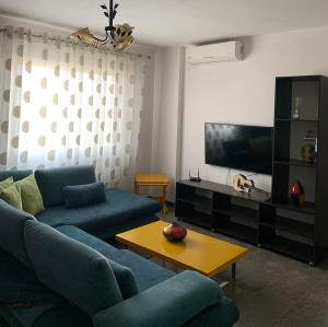 ein Wohnzimmer mit einem blauen Sofa und einem TV in der Unterkunft Quartz Apartament in Durrës