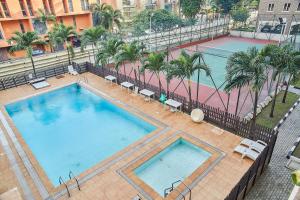 eine Aussicht über zwei Swimmingpools und einen Tennisplatz in der Unterkunft Impeccable 3-Bed luxury Apartment in ikoyi Lagos in Lagos