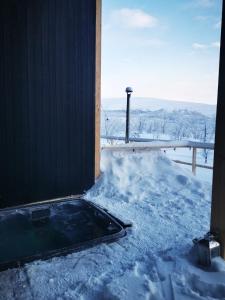 un bain à remous dans la neige à côté d'un bâtiment dans l'établissement Aurora View Lapland, Sky View Bedroom & Jacuzzi, à Kilpisjärvi