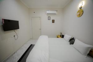 a white bedroom with a white bed and a tv at Stay Inn Kaashvi (A unit of Admire India Tourism Pvt. Ltd.) in Varanasi