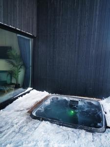 un bain à remous recouvert de neige à côté d'un bâtiment dans l'établissement Aurora View Lapland, Sky View Bedroom & Jacuzzi, à Kilpisjärvi