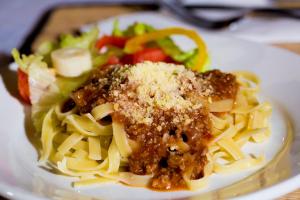 a plate of pasta with meat sauce and a salad at Ilha dos Poldros in Araioses +5 photos