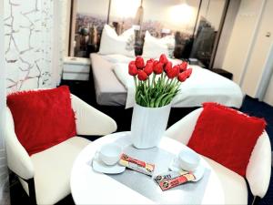 a vase of red tulips on a table in a hotel room at HORTENSJA 304 in Koszalin