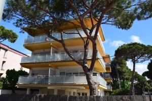 a yellow building with a tree in front of it at Castelldefels Playa in Castelldefels