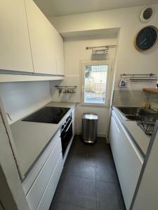een kleine keuken met witte kasten en een spoelbak bij Maison port guillaume in Dives-sur-Mer