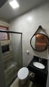 y baño con aseo, lavabo y espejo. en Suítes cambucá en Paraty