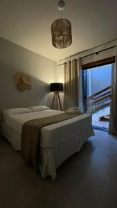 1 dormitorio con cama grande y ventana grande en Suítes cambucá en Parati
