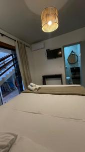 1 dormitorio con 1 cama blanca grande y luz en Suítes cambucá, en Paraty