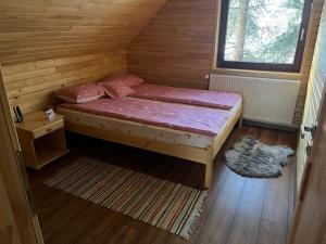 uma pequena cama num quarto de madeira com uma janela em Kispatak Vendégház em Ciumani