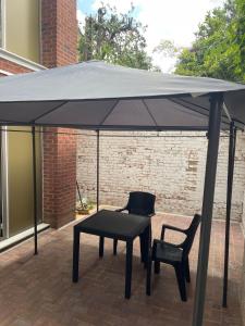 a black umbrella on a patio with two chairs and a table at 133 Cornwall Road n15 5ax in London